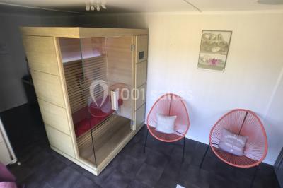 Intérieur d'un chalet en bois avec table, chaises recouvertes de fourrure, poêle allumé et vase de fleurs sur une table…