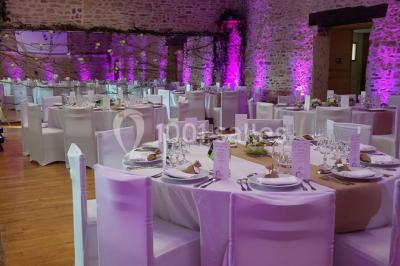 Intérieur d'un chalet en bois avec table, chaises recouvertes de fourrure, poêle allumé et vase de fleurs sur une table…