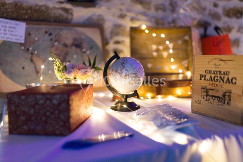 Décoration de table avec globe terrestre, boîte en bois, bouquet de fleurs et guirlandes lumineuses dans une ambiance…
