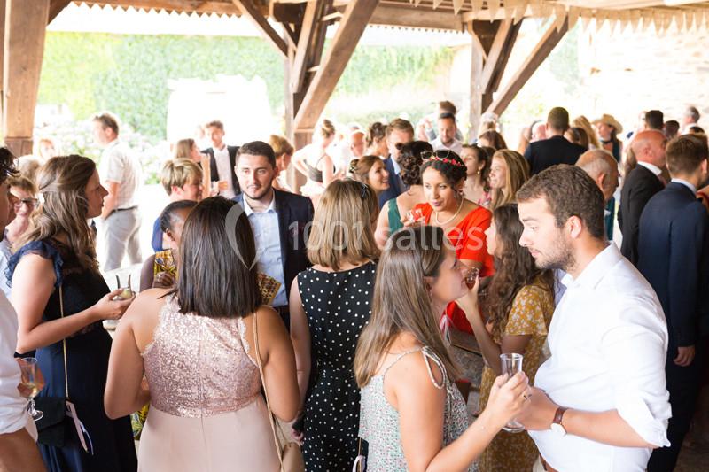 Groupe de personnes discutant et partageant un moment convivial lors d'un événement en extérieur sous un abri en bois.