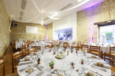 Intérieur d'un chalet en bois avec table, chaises recouvertes de fourrure, poêle allumé et vase de fleurs sur une table…