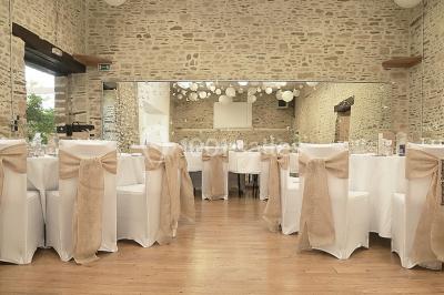 Intérieur d'un chalet en bois avec table, chaises recouvertes de fourrure, poêle allumé et vase de fleurs sur une table…