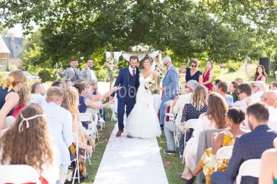 Intérieur d'un chalet en bois avec table, chaises recouvertes de fourrure, poêle allumé et vase de fleurs sur une table…