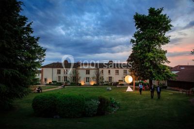 Des invités assis en plein air applaudissent lors d'une cérémonie sous des arbres aux feuilles partiellement jaunies.
