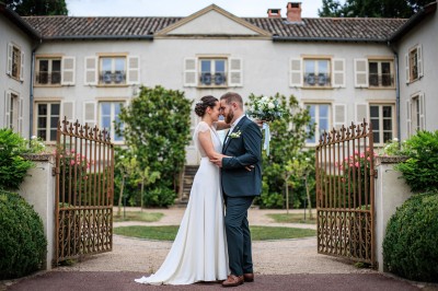 Des invités assis en plein air applaudissent lors d'une cérémonie sous des arbres aux feuilles partiellement jaunies.