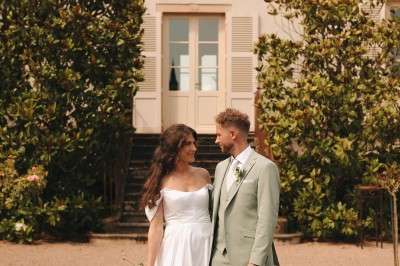Des invités assis en plein air applaudissent lors d'une cérémonie sous des arbres aux feuilles partiellement jaunies.