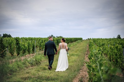 Des invités assis en plein air applaudissent lors d'une cérémonie sous des arbres aux feuilles partiellement jaunies.