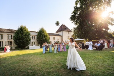 Des invités assis en plein air applaudissent lors d'une cérémonie sous des arbres aux feuilles partiellement jaunies.