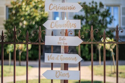 Des invités assis en plein air applaudissent lors d'une cérémonie sous des arbres aux feuilles partiellement jaunies.