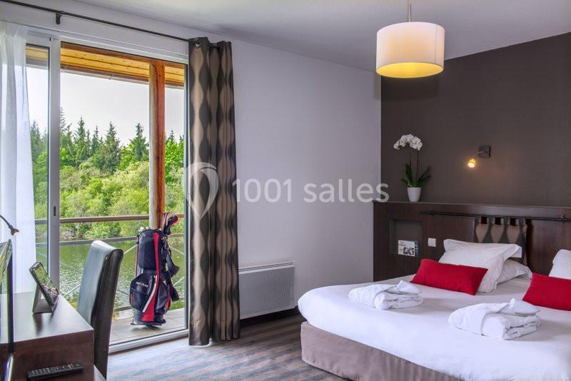 Chambre d'hôtel lumineuse avec lit double, bureau, balcon donnant sur un espace vert et sac de golf visible près de la porte.