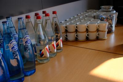 Bouteilles d'eau, tasses empilées et bocal de biscuits disposés sur une table en bois.