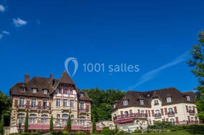 Chambre lumineuse avec parquet en bois, lit double, canapé rouge, table basse et grandes fenêtres avec rideaux fleuris.