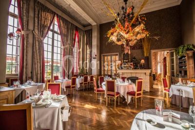 Chambre lumineuse avec parquet en bois, lit double, canapé rouge, table basse et grandes fenêtres avec rideaux fleuris.