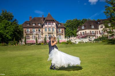 Chambre lumineuse avec parquet en bois, lit double, canapé rouge, table basse et grandes fenêtres avec rideaux fleuris.