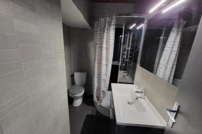 Grande maison en pierre entourée de verdure, avec une cour ensoleillée et des arbres en arrière-plan.