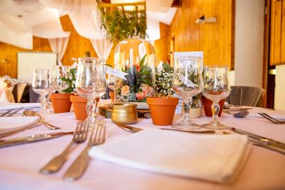 Grande maison en pierre entourée de verdure, avec une cour ensoleillée et des arbres en arrière-plan.
