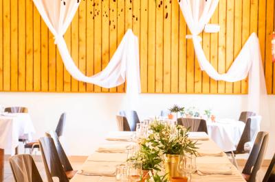 Grande maison en pierre entourée de verdure, avec une cour ensoleillée et des arbres en arrière-plan.