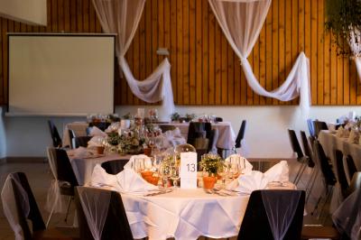 Grande maison en pierre entourée de verdure, avec une cour ensoleillée et des arbres en arrière-plan.