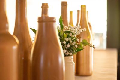 Grande maison en pierre entourée de verdure, avec une cour ensoleillée et des arbres en arrière-plan.