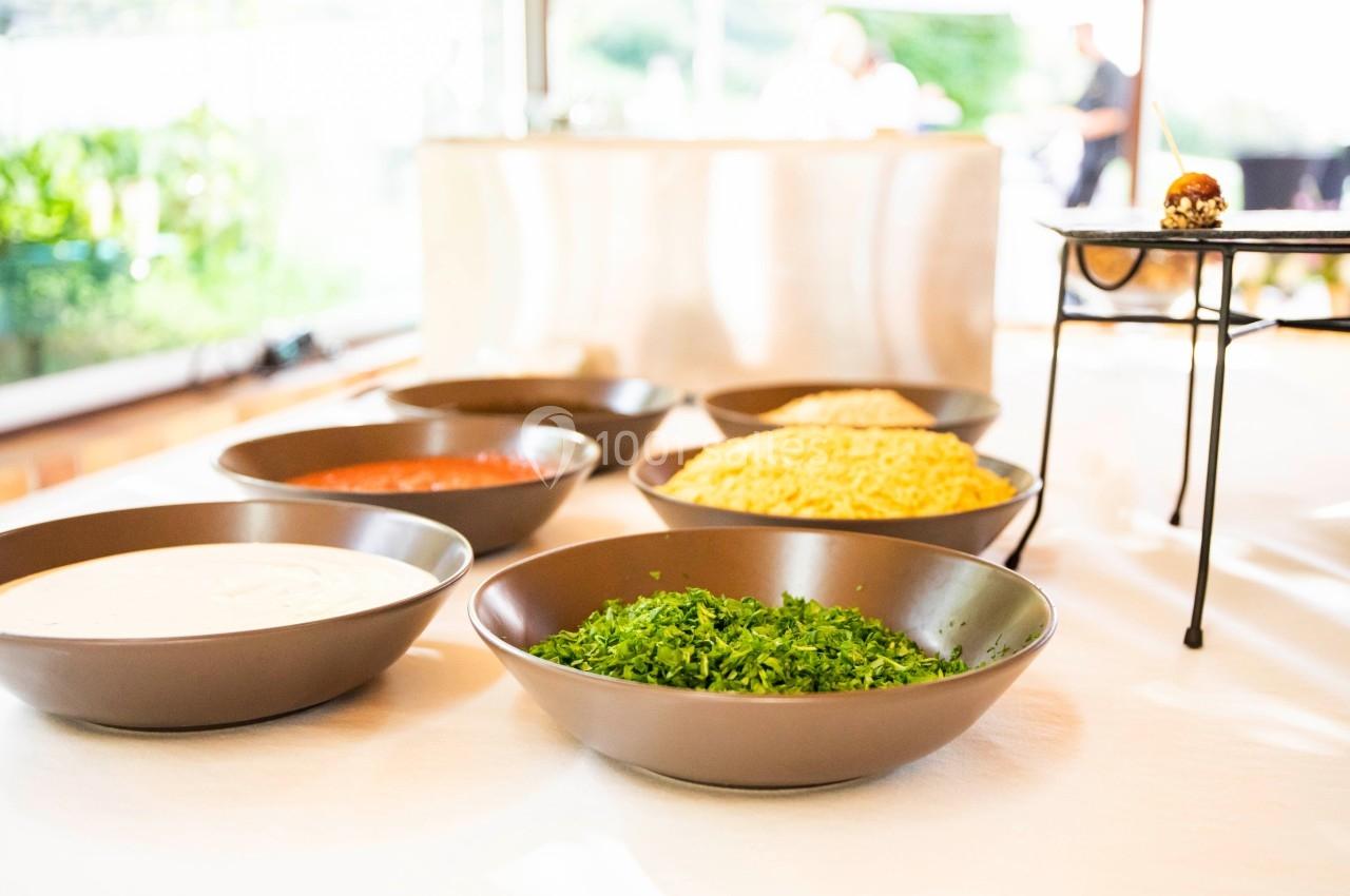 Assortiment de bols contenant des ingrédients variés, dont des herbes fraîches, des sauces et des céréales, sur une table…