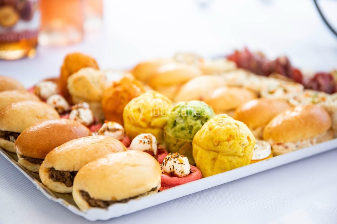 Plateau de mini-sandwichs et bouchées variées colorées disposées sur une table blanche.