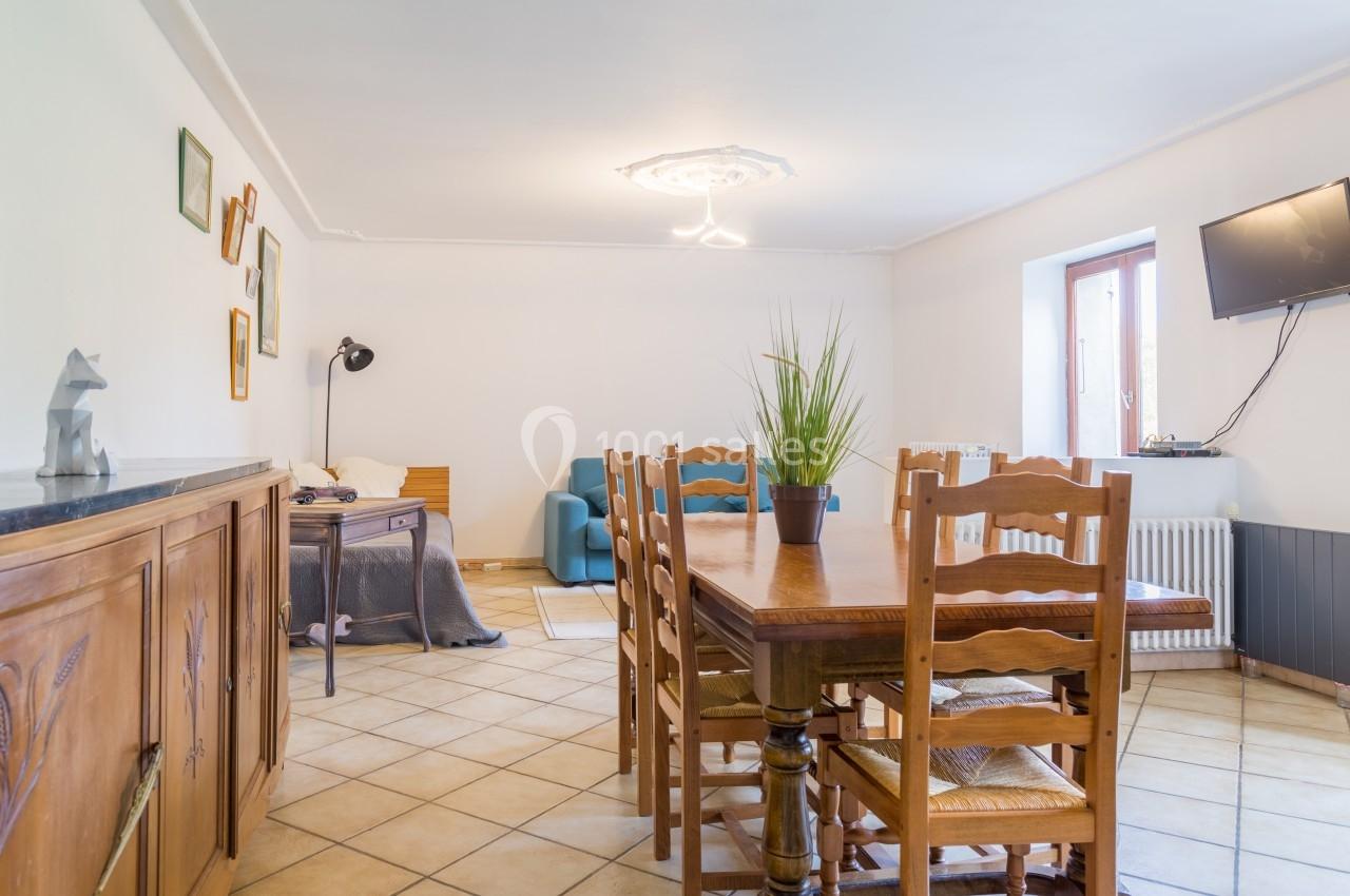 Salle à manger avec table en bois, chaises assorties, canapé bleu, lampe sur pied et décoration murale.