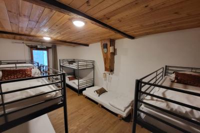 Grande maison en pierre entourée de verdure, avec une cour ensoleillée et des arbres en arrière-plan.