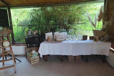 Grande maison en pierre entourée de verdure, avec une cour ensoleillée et des arbres en arrière-plan.