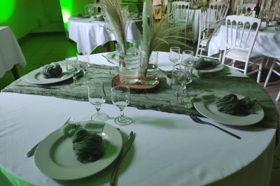 Grande maison en pierre entourée de verdure, avec une cour ensoleillée et des arbres en arrière-plan.