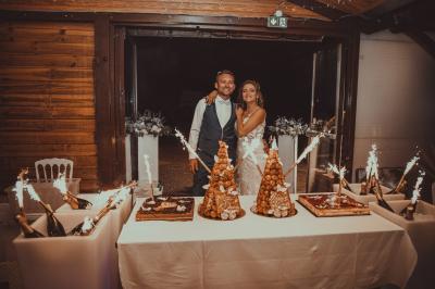 Grande maison en pierre entourée de verdure, avec une cour ensoleillée et des arbres en arrière-plan.