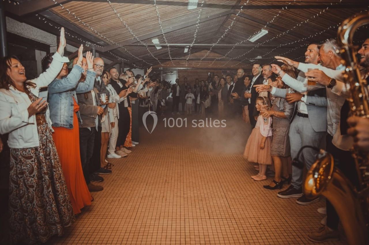 Des personnes alignées des deux côtés d'un passage intérieur applaudissent et célèbrent dans une ambiance festive.