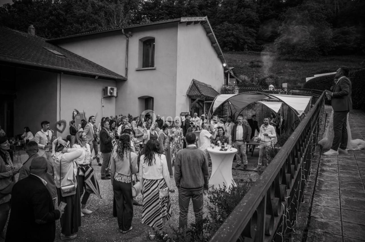 Groupe de personnes rassemblées dans une cour extérieure lors d'un événement, près d'une maison et d'une tonnelle.