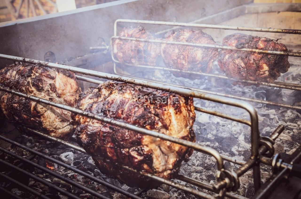 Viandes rôtissant sur des broches au-dessus de braises dans un barbecue en plein air.