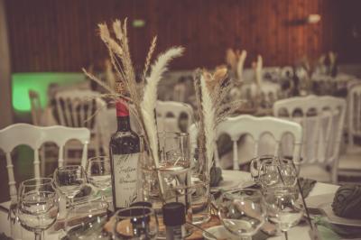 Grande maison en pierre entourée de verdure, avec une cour ensoleillée et des arbres en arrière-plan.