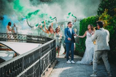Grande maison en pierre entourée de verdure, avec une cour ensoleillée et des arbres en arrière-plan.