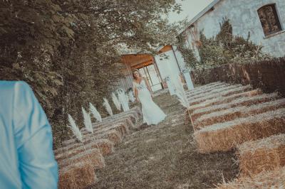 Grande maison en pierre entourée de verdure, avec une cour ensoleillée et des arbres en arrière-plan.