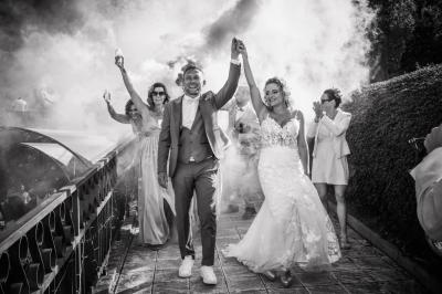 Grande maison en pierre entourée de verdure, avec une cour ensoleillée et des arbres en arrière-plan.