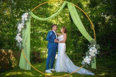 Grande maison en pierre entourée de verdure, avec une cour ensoleillée et des arbres en arrière-plan.