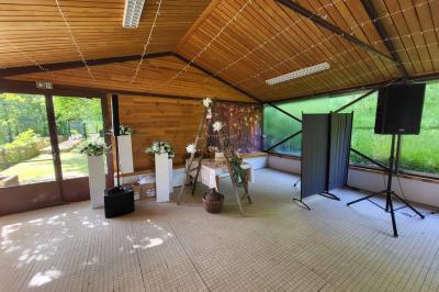 Grande maison en pierre entourée de verdure, avec une cour ensoleillée et des arbres en arrière-plan.