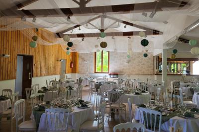 Grande maison en pierre entourée de verdure, avec une cour ensoleillée et des arbres en arrière-plan.