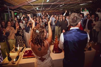 Grande maison en pierre entourée de verdure, avec une cour ensoleillée et des arbres en arrière-plan.