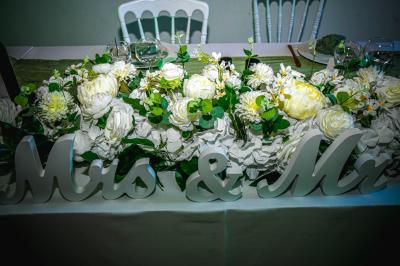 Grande maison en pierre entourée de verdure, avec une cour ensoleillée et des arbres en arrière-plan.