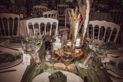 Grande maison en pierre entourée de verdure, avec une cour ensoleillée et des arbres en arrière-plan.