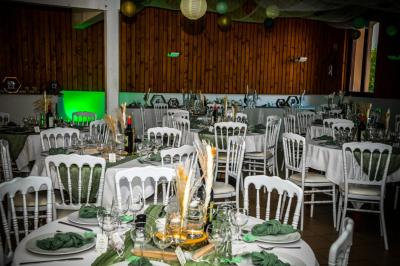 Grande maison en pierre entourée de verdure, avec une cour ensoleillée et des arbres en arrière-plan.