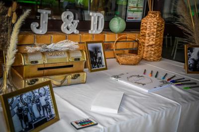 Grande maison en pierre entourée de verdure, avec une cour ensoleillée et des arbres en arrière-plan.