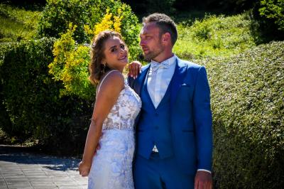 Grande maison en pierre entourée de verdure, avec une cour ensoleillée et des arbres en arrière-plan.