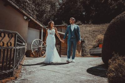 Grande maison en pierre entourée de verdure, avec une cour ensoleillée et des arbres en arrière-plan.