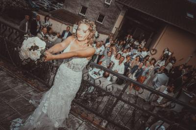 Grande maison en pierre entourée de verdure, avec une cour ensoleillée et des arbres en arrière-plan.