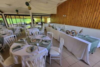 Grande maison en pierre entourée de verdure, avec une cour ensoleillée et des arbres en arrière-plan.