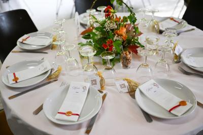 Grande maison en pierre entourée de verdure, avec une cour ensoleillée et des arbres en arrière-plan.